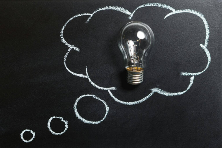 Light bulb laying on chalkboard with drawn thought bubble, symbolizing creative ideas.